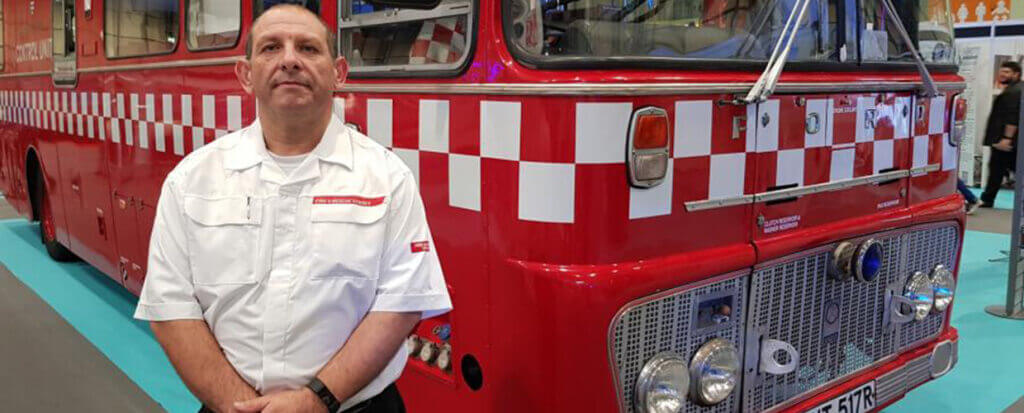 A firefighter standing in front of an old firetruck