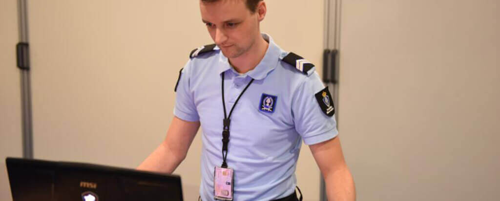 A police officer standing behind his laptop
