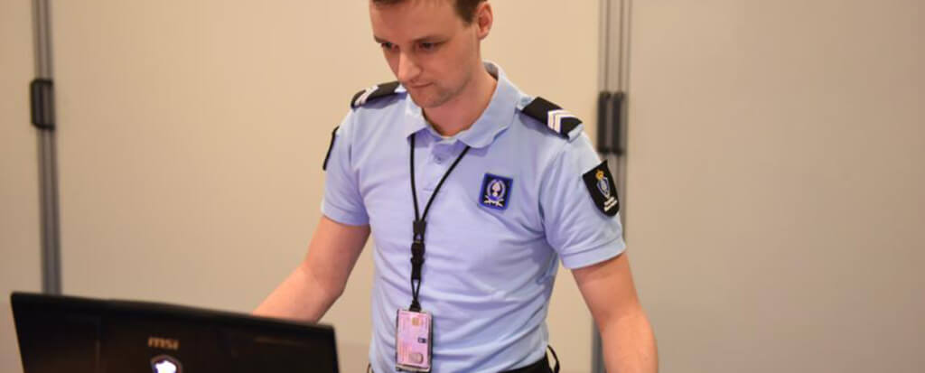 A police officer standing behind his laptop